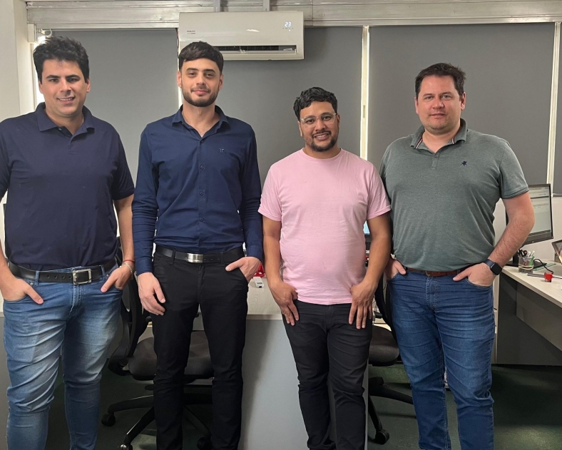 Cuatro hombres de pie en una oficina con escritorios